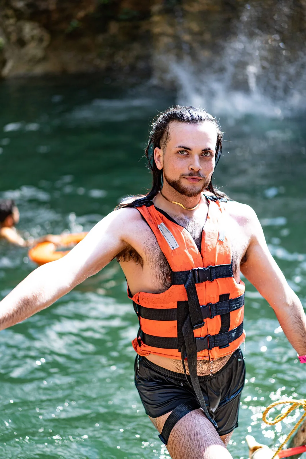 A retreat attendee standing in a cenote with a life vest, enjoying the refreshing natural waters